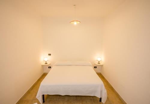 um quarto branco com uma cama e 2 candeeiros em On the beach em Torre Lapillo