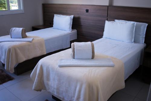 Habitación de hotel con 2 camas con sábanas blancas en Sokulski Flat Hotel e Restaurante, en Araucária