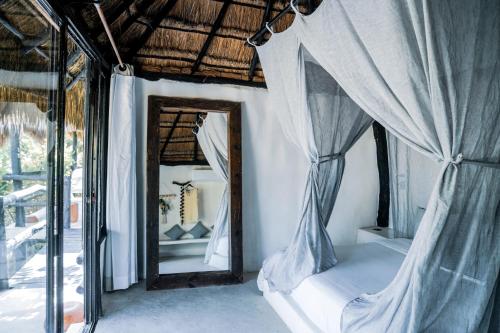 a bedroom with a mirror and a bed with curtains at Coco Tulum Zen Zone Hotel in Tulum