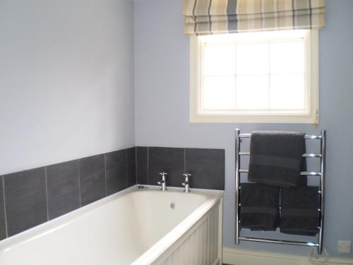 ein Bad mit einer Badewanne und einem Fenster in der Unterkunft Duken Courtyard Cottage in Bridgnorth
