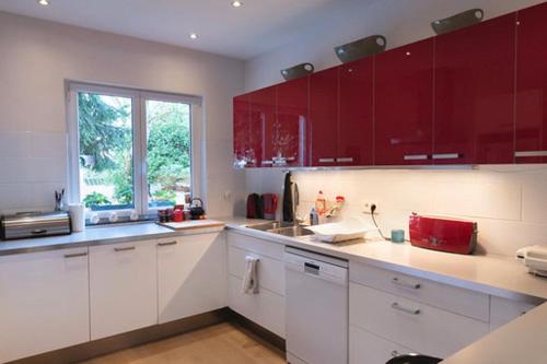 una cocina con encimeras blancas y armarios rojos en Modern duplex with garden en Bruselas