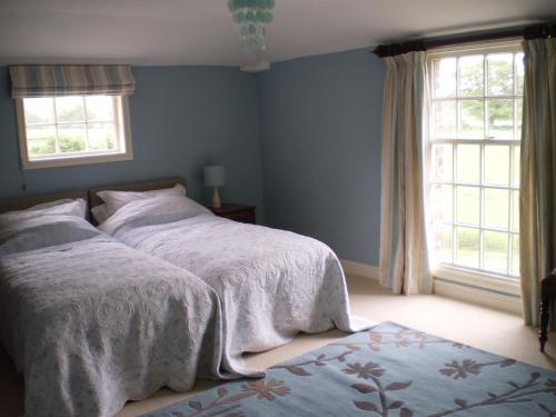 1 dormitorio con 2 camas y 2 ventanas en Duken Courtyard Cottage, en Bridgnorth