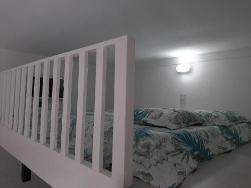 a white bedroom with a bed and a crib at Apartamento Guarujá - Pitangueiras in Guarujá