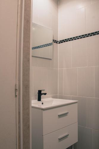 une salle de bain blanche avec un lavabo et un miroir dans l'établissement T2 BedinSaumur LOIRE CHATEAU tout CONFORT, à Saumur