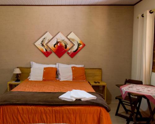 a bedroom with a bed with paintings on the wall at Chalés do Pardal in Visconde De Maua