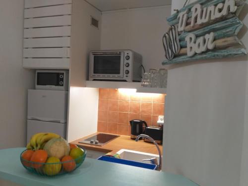 a kitchen with a bowl of fruit on a counter at MANGANAO LOFTS INN Bord de Mer in Saint-François