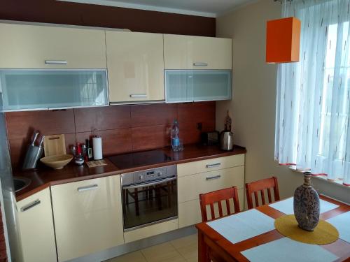 a kitchen with white cabinets and a wooden table with a tableablish at Green Apartment in Olsztyn