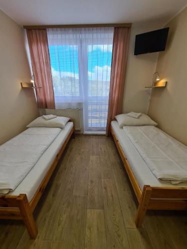 two beds in a room with a window at Stredisko Lipka in Bardejov