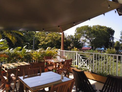 une terrasse avec des tables et des chaises sous un parasol dans l'établissement Gites Rose des Vents, à Deshaies