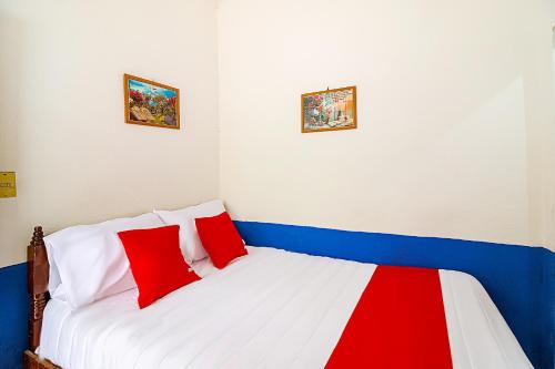 a room with a bed with red and white pillows at OYO Hotel Posada Los Faroles,Tabasco in Villahermosa