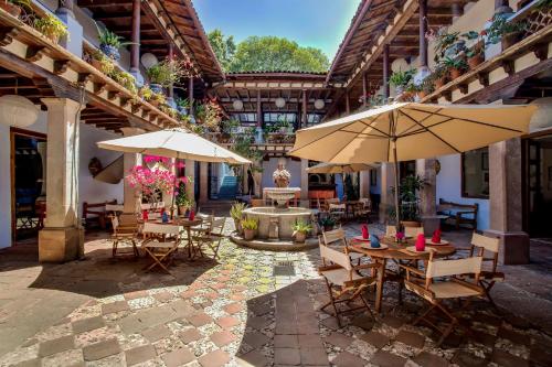 un patio al aire libre con mesas, sombrillas y una fuente. en Hotel Boutique La Batucada en Valle de Bravo