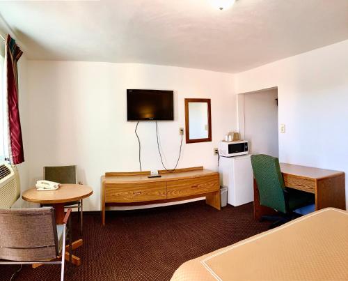 a hotel room with a bed and a desk and a television at Desert Inn in Van Horn