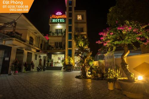a street at night with a hotel sign and plants at Magnolia Hotel Cam Ranh in Cam Ranh