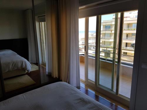 a bedroom with a bed and a large glass window at Facing the Sea in Furadouro