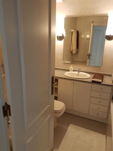a bathroom with a toilet and a sink and a mirror at Facing the Sea in Furadouro