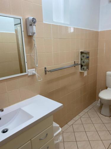 a bathroom with a toilet and a phone on the wall at Paddle Steamer Motel in Swan Hill