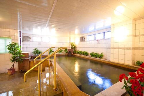 una piscina de agua en una habitación con plantas en Beppu Station Hotel en Beppu