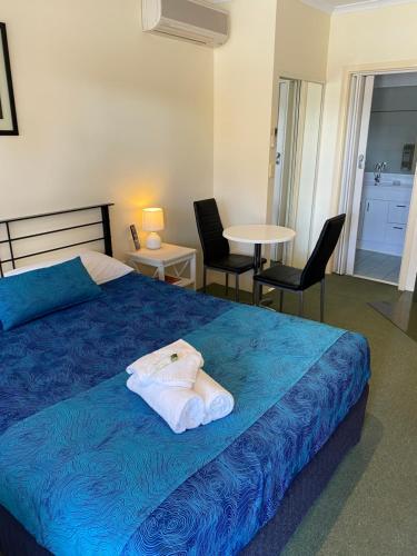 a bedroom with a blue bed and a table and chairs at Paddle Steamer Motel in Swan Hill