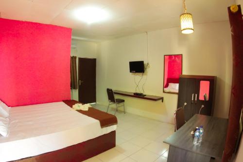a bedroom with a large bed with a red wall at FX72 Beach Resort Maumere in Maumere