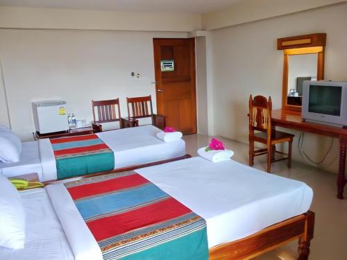 a room with three beds and a desk and a television at ทรัพย์มุกดา แกรนด์ โฮเทล Submukda Grand Hotel in Mukdahan