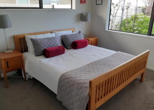 Un dormitorio con una cama grande con dos almohadas rojas. en Glen Wallace Lodge, en Waipu