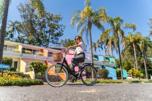 a woman riding a bike down a street at The Cubana Resort Nambucca Heads in Nambucca Heads