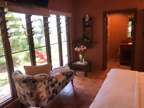 un soggiorno con divano, tavolo e finestre di Gunnadoo Holiday Hut with Ocean Views and Jacuzzi a Miallo