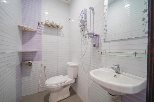 a white bathroom with a toilet and a sink at CMN Hotel & Homestay in Sungai Petani