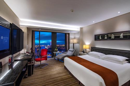 a hotel room with a large bed and a television at Pullman Guiyang in Guiyang