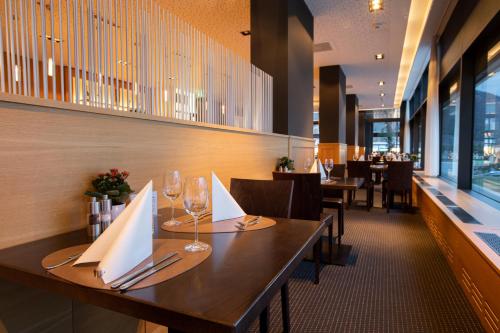 a restaurant with a long wooden table with wine glasses at Mercure Chur City West in Chur