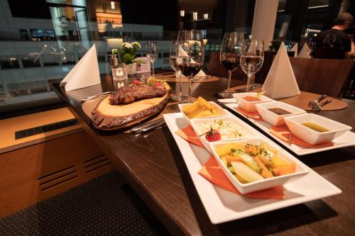 a table with plates of food and glasses of wine at Mercure Chur City West in Chur
