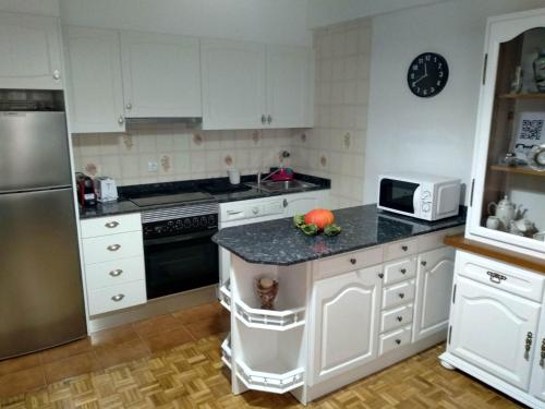 eine Küche mit weißen Schränken und einer Granitarbeitsplatte in der Unterkunft CASA DANIELA Apartamentos in Estella