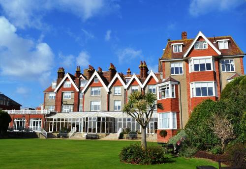 a large brick building with a green lawn at Hydro Hotel in Eastbourne