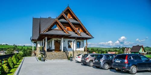 a small house with cars parked in a parking lot at Willa na Borku in Ciche