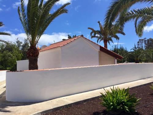 a white fence in front of a house with palm trees at Rio Sol - Oasis de Privacidad in Costa Calma