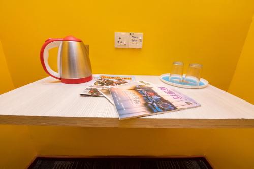 einen Tisch mit einer Teekanne, eine Zeitschrift und Gläser in der Unterkunft Madani Hotel in Cameron Highlands