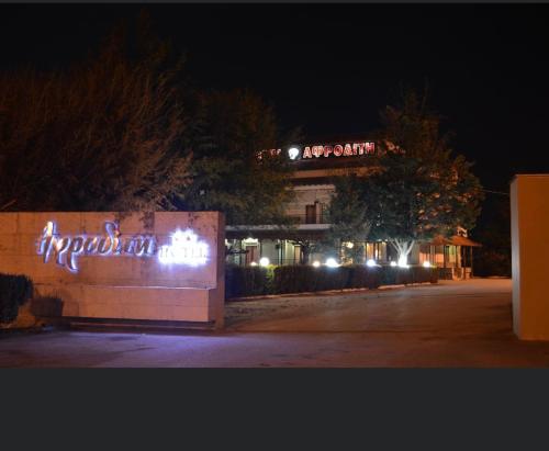 a building with a sign in front of it at night at Αφροδίτη Hotel in Néon Rýsion