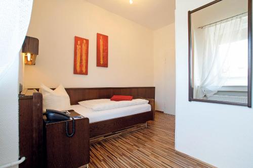 a small bedroom with a bed and a mirror at Hotel Deutsches Haus in Braunschweig
