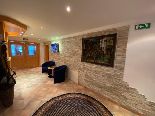 a lobby with a stone wall and blue chairs at Chasa Monthani in Ischgl
