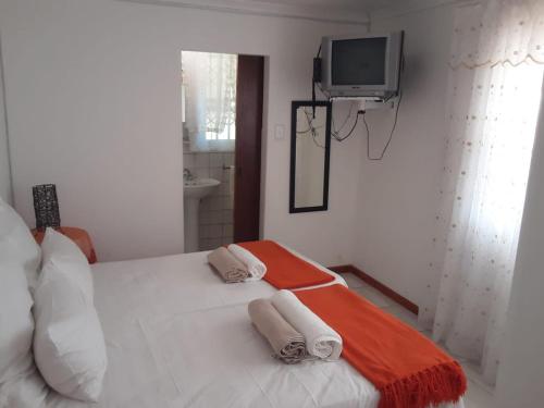 a bedroom with a white bed and a tv on the wall at Yonz Self Catering Units in Port Alfred