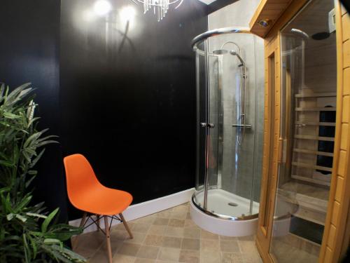 a bathroom with a shower and a orange chair at Les Deux Rives in Cierp