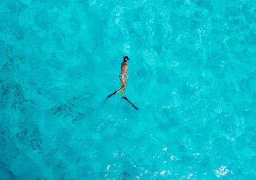 a person on water skis in the blue water at Soneva Fushi in Baa Atoll