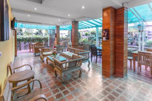 a restaurant with wooden benches and tables and chairs at Yellow Tique Hotel in Lampang