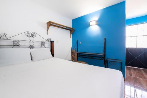 1 dormitorio con 1 cama blanca y paredes azules en OYO Casa Vieja,Ciudad Serdán,Museo La Magnolia en Ciudad Serdán