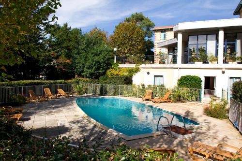 a swimming pool with chairs and a house at Résidence de Tourisme Vacances Bleues Villa Regina in Arcachon