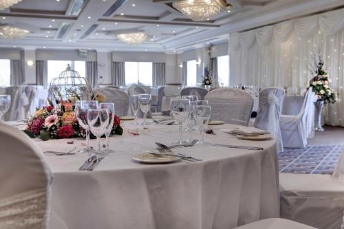 a dining room with a table with glasses and flowers at Windmill Village Hotel, Golf Club & Spa, BW Signature Collection in Coventry