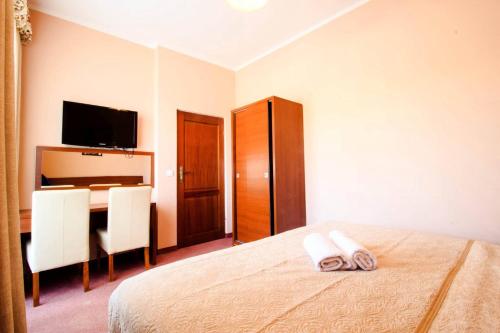 a bedroom with a bed and a table and a television at Willa Stożek, 50 m od term i wyciągów narciarskich in Białka Tatrzanska