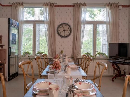 a dining room with a table and a clock on the wall at B&B Villa Aurora in Hanko