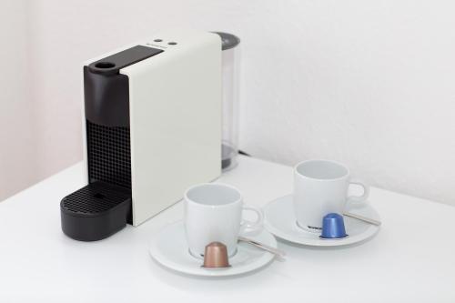 a coffee maker and three cups on a table at Hotel Reverey * kontaktloser Self Check-In * in Hannover
