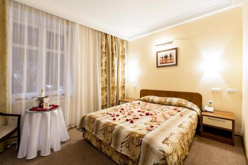 a hotel room with a bed and a table with roses on it at Hotel Retro in Novokuybyshevsk
